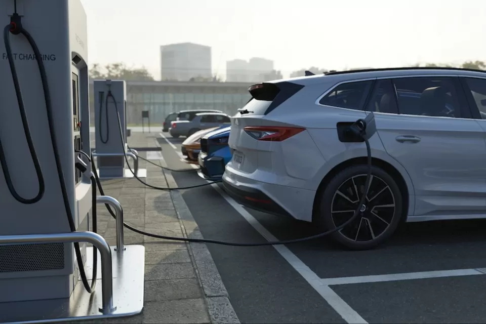 Row of vehicles parked and plugged in at EV charging station.
